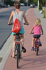 Foto von einer Mutter und einem Kind, die auf einem Fahrradweg Rad fahren